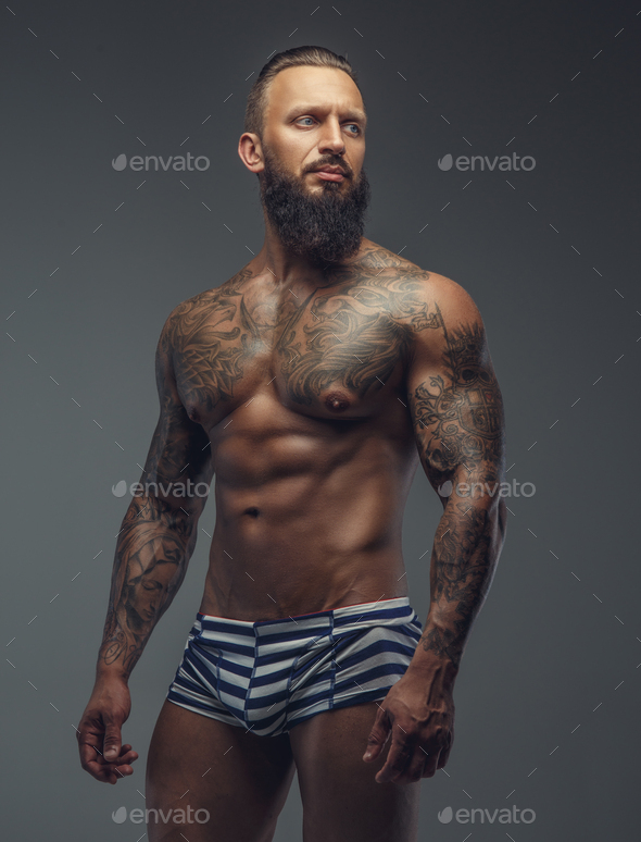 Tattooed muscular man with beard in stripes panties. Stock Photo by fxquadro