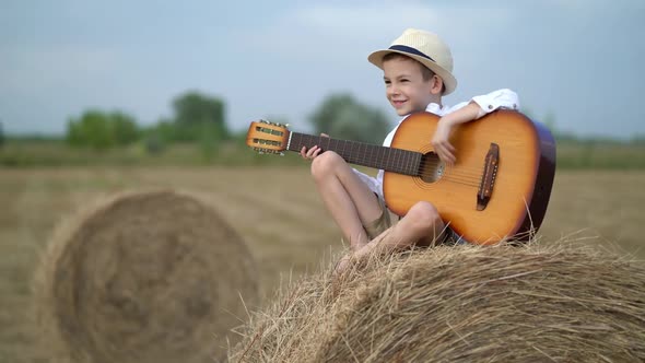 Little Boy on a Haystack with a Guitar