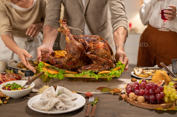 Young and matue men holding tray with homemade roasted turkey over