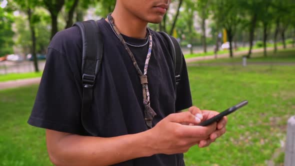 Handsome Guy Typing Message on Mobile Outdoors alt