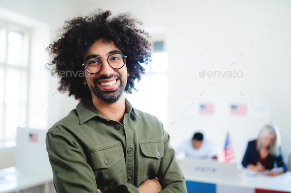 Portrait of happy mixed-race man looking at camera in the polling place, usa elections.