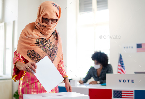 Islamic woman voter putting her vote in the ballot box, usa elections and coronavirus