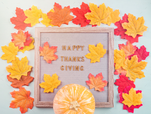 Happy thanksgiving greetings on letter board with pumpkin and autumn leaves around. Seasonal flat lay