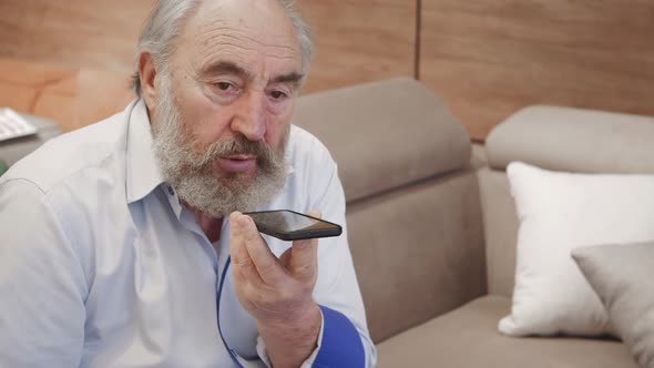 Old man using smart phone voice recognition, dictates thoughts, voice dialing message alt
