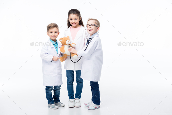 Adorable smiling kids playing doctors with stethoscope, reflex hammer and teddy bear isolated on