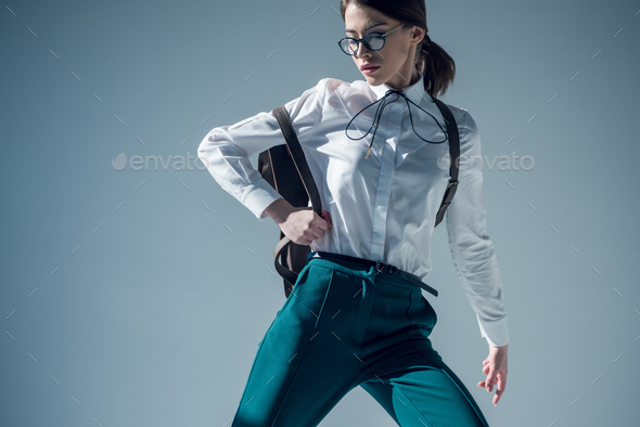 stylish hipster woman in white shirt, green trousers and glasses with backpack