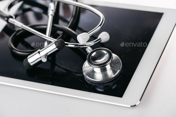 close up view of reflex hammer and stethoscope on digital tablet on white