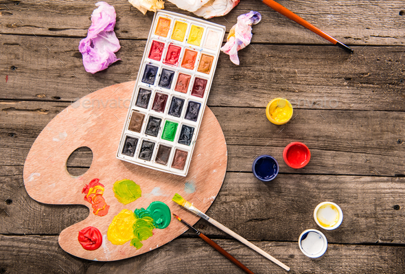 top view of paints, paintbrushes and palette on table