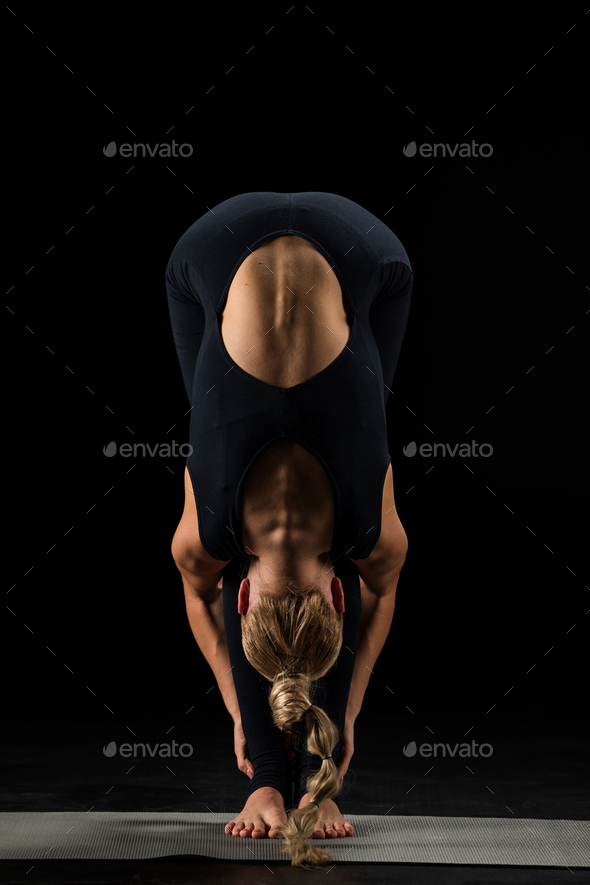 Woman practicing yoga performing Uttanasana or The Standing Forward Bend Pose isolated on black