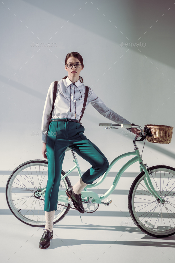 full length of young stylish hipster woman in glasses, white shirt and green trousers with hipster