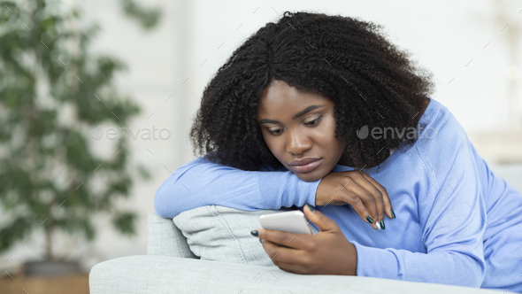 Frustrated lady checking mobile phone sitting on the couch