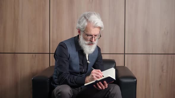 Elegant Grayhaired Man Designer Works in the Office Art Director Writes Down Ideas and Concepts in a alt