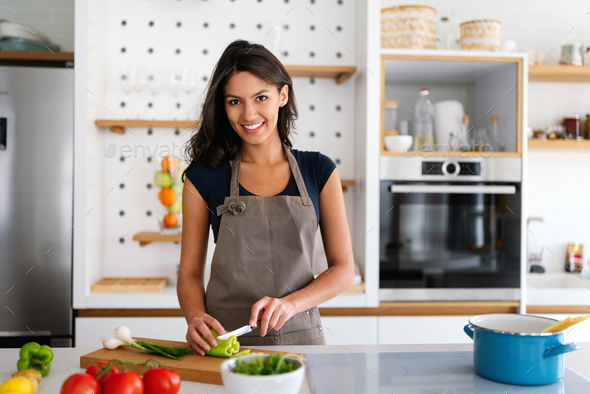 Beautiful woman making salad in kitchen smiling and laughing happy and cheerful.