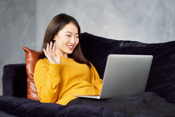 Asian woman waving hands looking to laptop. Online dating, meeting with friends