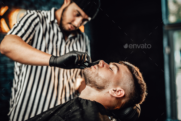 Barber cleaning face of his customer with brush