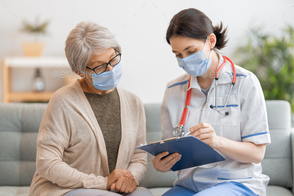 Doctor and senior woman wearing facemasks - Stock Photo - Images