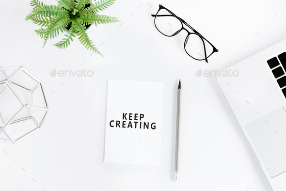 flat lay with Keep creating motivational quote on modern workplace with laptop