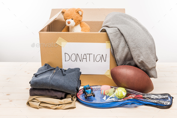 cardboard box with donation clothes and different objects isolated on white, donation concept