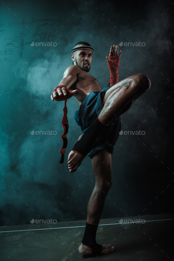 Low angle view of determined Muay thai fighter training thai boxing, ultimate fight concept