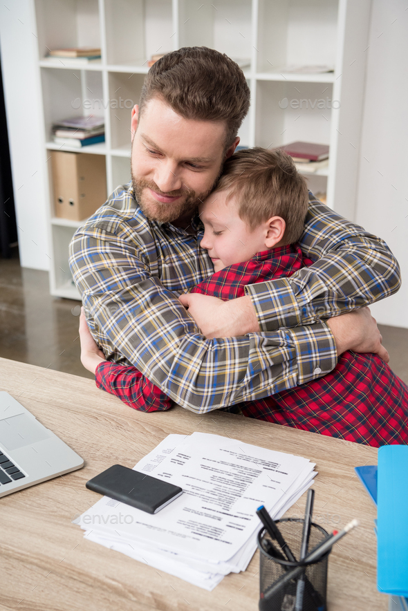 Father businessman hugs his son at home office