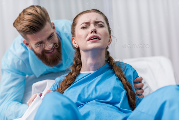 Pregnant Woman Giving Birth In Hospital While Man Hugging Her Stock Photo By Lightfieldstudios