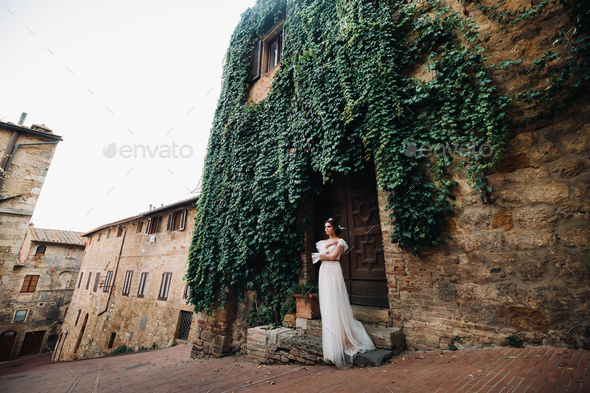 A bride in a white dress in the old town of San Gimignano.A girl walks around the city in Italy.Tuscany
