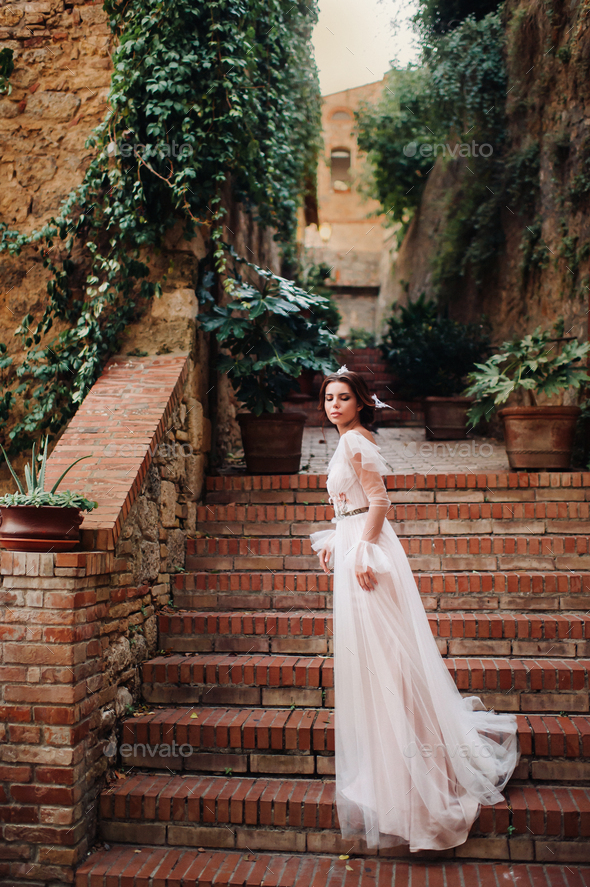 A bride in a white dress in the old town of San Gimignano.A girl walks around the city in Italy.Tuscany