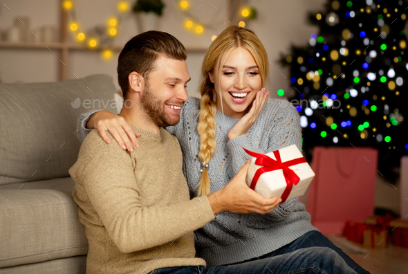 Emotional woman looking at Christmas gift in her man hands - Stock Photo - Images