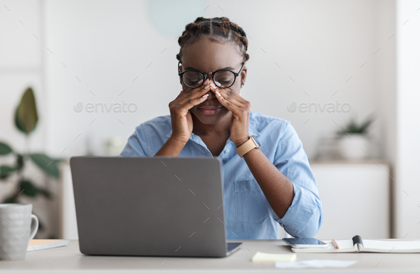 Eye Strain. Tired African Female Office Worker Sitting At Workplace Massaging Nosebridge