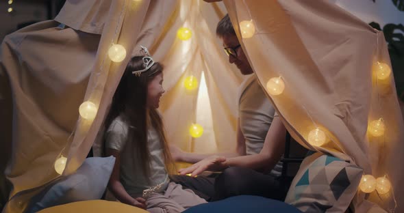 Happy Father and Daughter Playing in Toy Wigwam and Having Fun alt