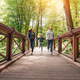 young happy interracial family running through the wooden bridge in sunny forest - PhotoDune Item for Sale