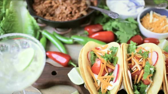 Ground beef tacos with romaine lettuce, diced tomatoes, radishes, and shredded cheddar cheese. alt