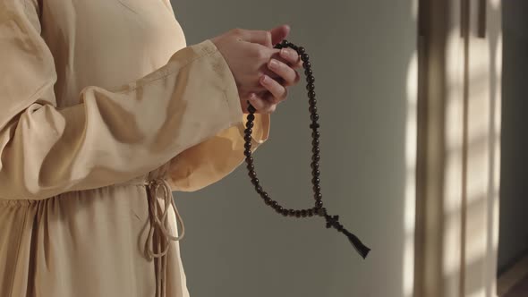 Unrecognizable Woman Holding Rosary Beads and Praying Heartily alt