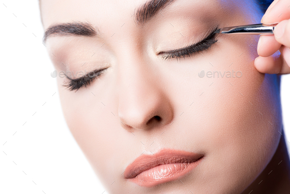 Makeup artist applying eyeliner arrows on face. hand of woman using makeup brush