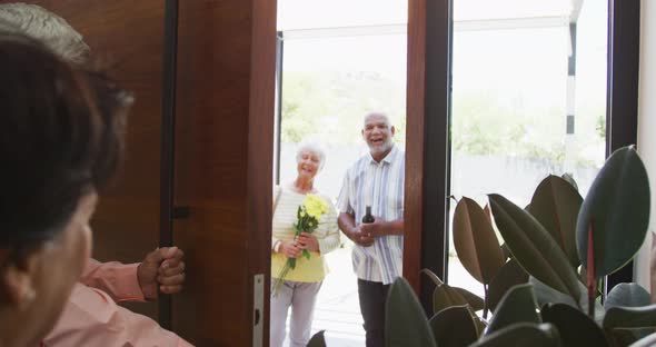 Happy senior biracial couple opening door at retirement home alt