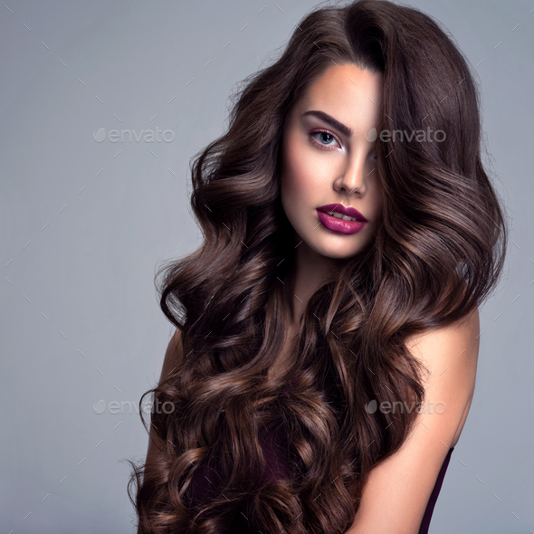 Fashion model with wavy hairstyle. Attractive young girl with curly hair  posing at studio. Stock Photo by valuavitaly
