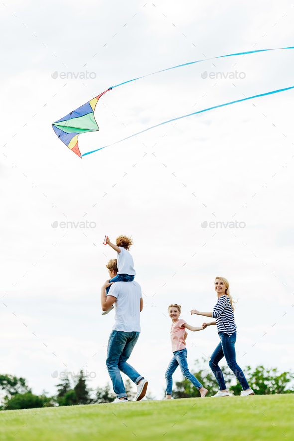 happy family with two kids playing with kite at park