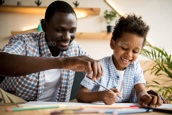 beautiful happy african american father and son drawing together in ...