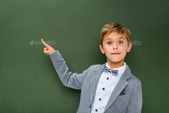 schoolboy pointing at copy space next to chalkboard