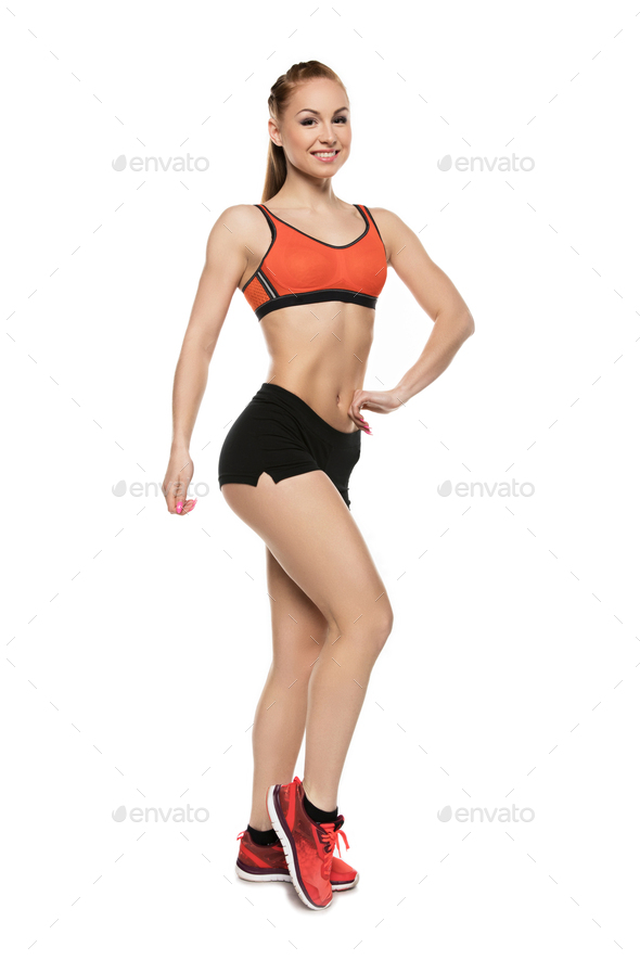 Hands on the waist, standing. Young caucasian woman with athletic