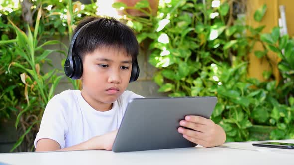 Asian boy using tablet to study online.