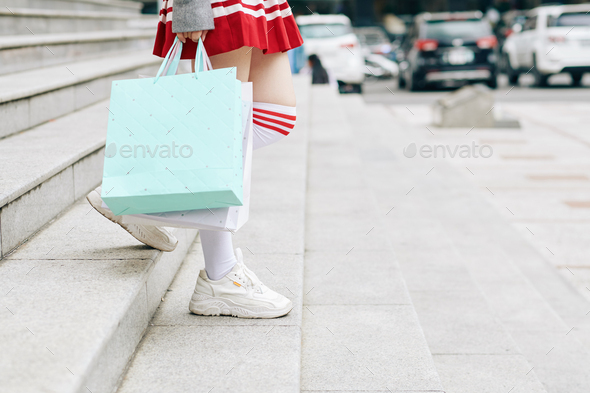 Korean school girl leaving mall with shopping bags in hands