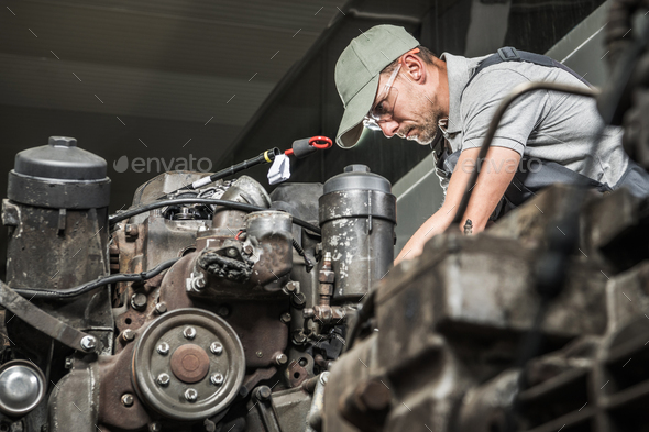 Forty Years Old Caucasian Diesel Engines Automotive Technician Restoring Truck Engine. Automotive Industry Theme.