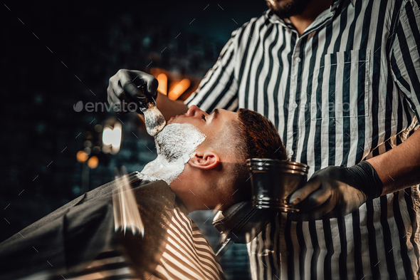 Professional barber in black gloves preparing his client Stock Photo by