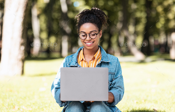 E-Learning. African American Female Student Using Laptop Computer Learning Online Browsing Internet Sitting In Park Outdoors. Distant Education, Educational Website Concept