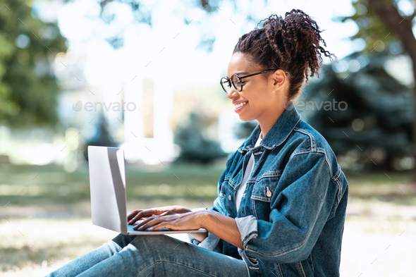Black Freelancer Woman Using Laptop Working Online, Browsing Internet Sitting In City Park Outside. Freelance Career Lifestyle, Remote Web Business, Distant E-Learning Concept