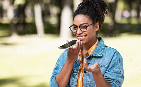 Happy Black Lady Talking On Cellphone Using Loudspeaker Walking Outdoors