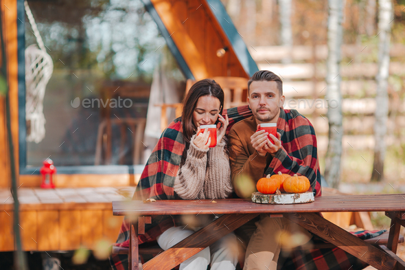 Young couple sitting on the wooden old table at autumn day