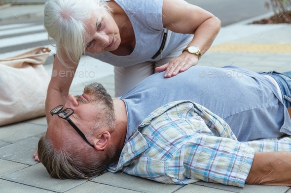 Helpful passerby checks the vital functions of the person who fainted on the street