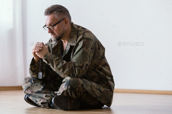 Middle aged veteran holding a dog tag of his dead friend